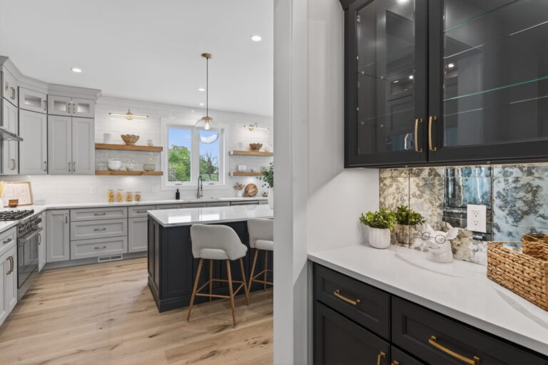 Kitchen with gray cabinets, a navy island, gold hardware, and bar stools
