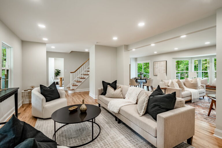 Open-concept living room with a sectional sofa, hardwood floors, and large windows