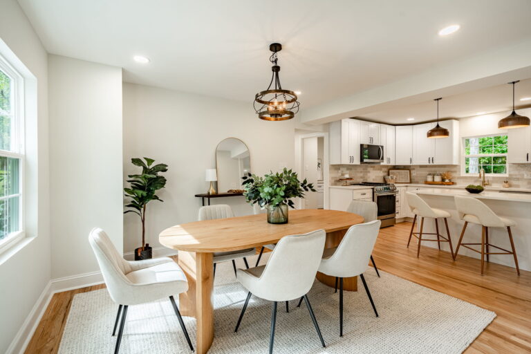 Dining area with a wood table and white chairs open to a modern kitchen