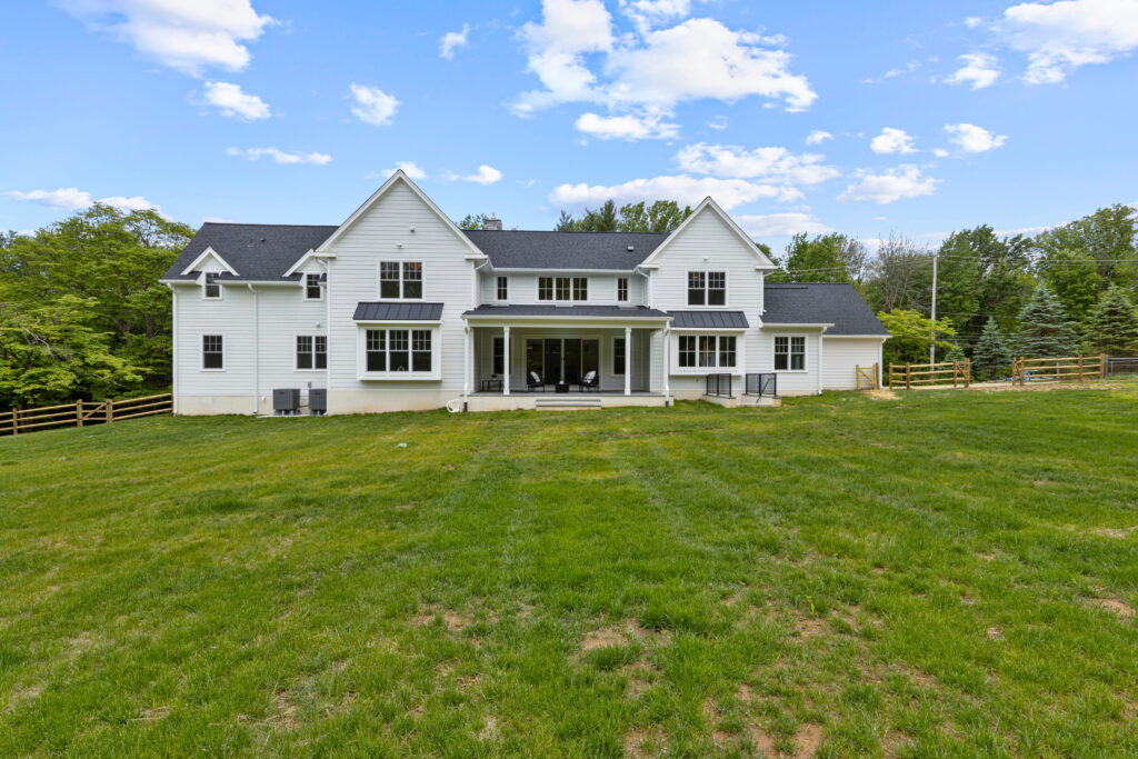 White farmhouse-style home set back across a large green lawn