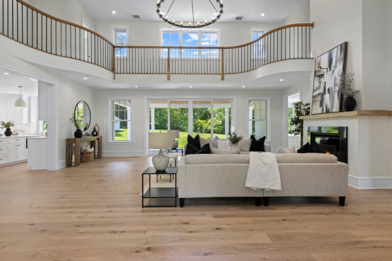 Two-story great room with a wall of windows, a sectional sofa, and a loft balcony