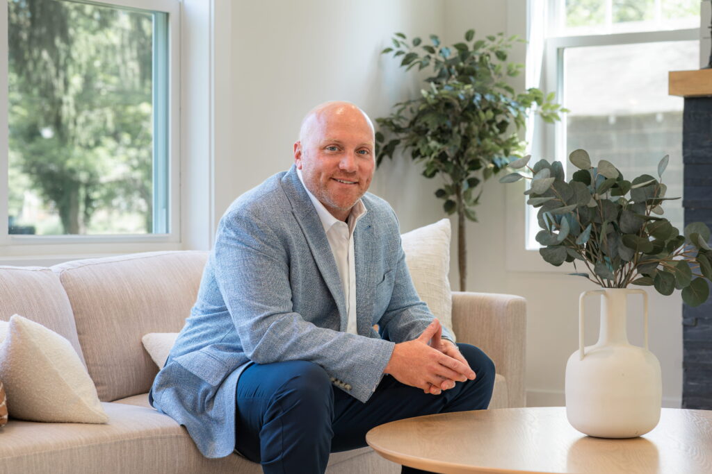 Realtor Ryan DiCecco seated on a living room sofa, smiling