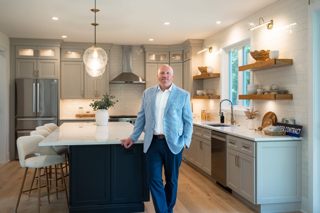 Realtor Ryan DiCecco standing by the island in a bright modern kitchen
