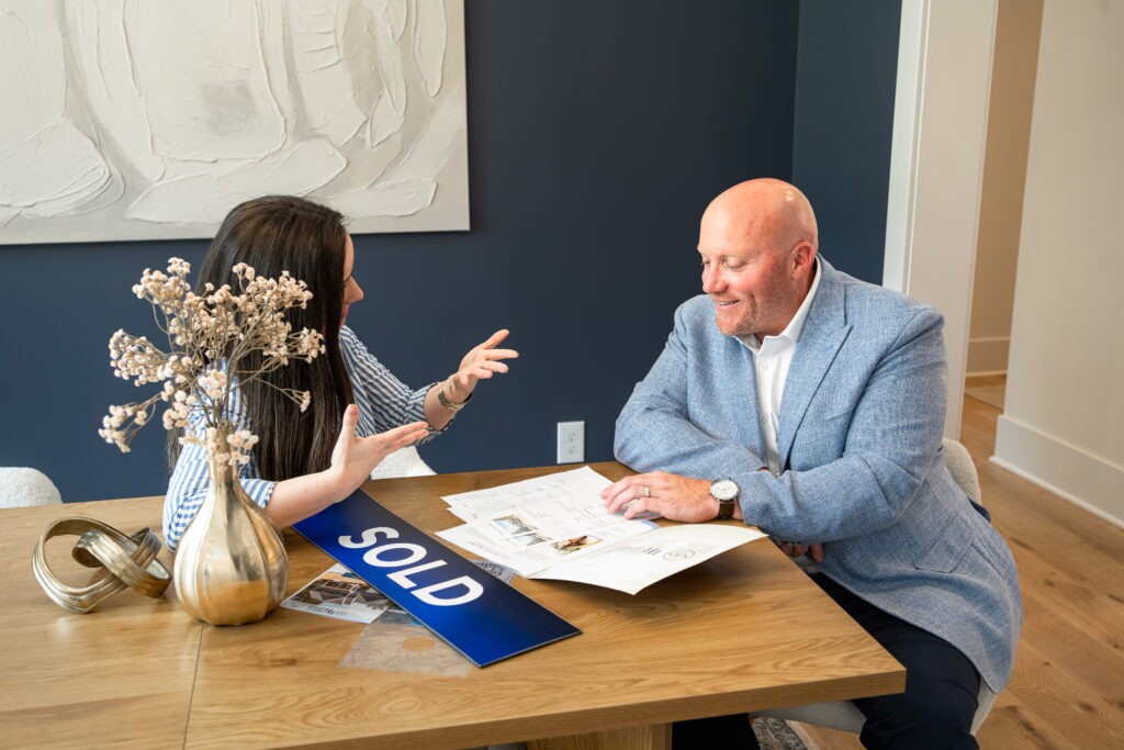 Realtor Ryan DiCecco reviewing paperwork with clients beside a SOLD sign